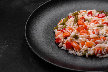 Delicious fresh risotto with vegetables, spices and herbs on a black plate