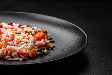 Delicious fresh risotto with vegetables, spices and herbs on a black plate