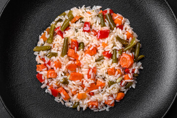 Delicious fresh risotto with vegetables, spices and herbs on a black plate