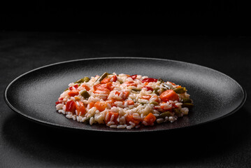 Delicious fresh risotto with vegetables, spices and herbs on a black plate