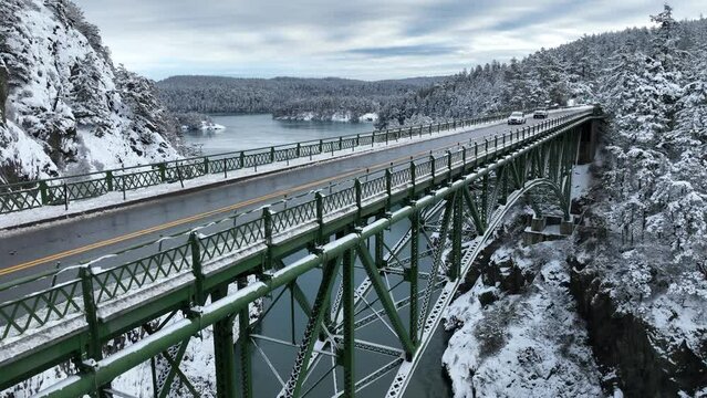 Rising aerial shot of cars driving across a bridge with snow everywhere.