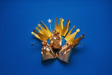 Happy Epiphany Day, Three Kings Day greeting card with three gold crowns and gifts on blue...
