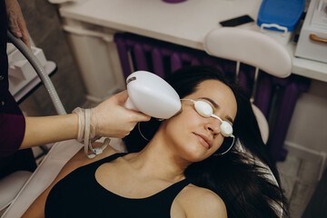 partial view of young woman receiving laser hair removal epilation on face in salon