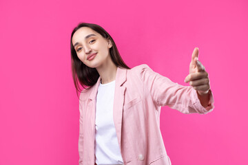 Happy young caucasian female in a pink jacket pointing fingers away