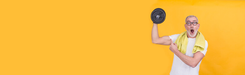 mature man with dumbbells on yellow background
