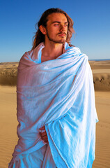 Holy, handsome man in white robe in desert looks like Jesus