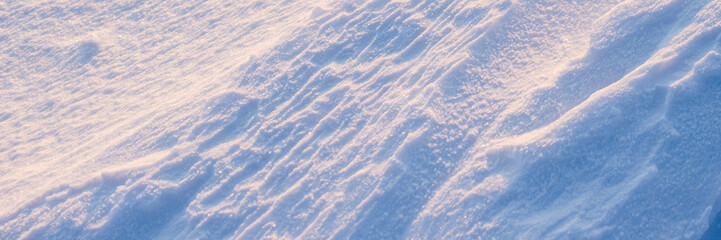 Beautiful winter background with snowy ground. Natural snow texture. Wind sculpted patterns on snow surface. Wide panoramic texture for background and design.