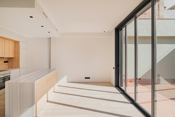 Large bright spacious kitchen with wooden furniture and closed black metal sliding glass doors with...