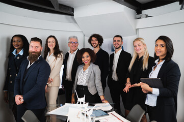 Multiracial group of colleagues standing and looking at camera. Smiling businesspeople in elegant suits.