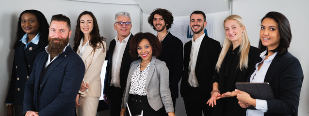Horizontal banner or header Multiracial group of colleagues standing and looking at camera. Smiling businesspeople in elegant suits.