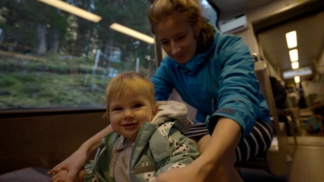 Mother holds little daughter sitting near big window in train. Woman and girl child enjoy vacation to Switzerland by railway transport closeup slow motion