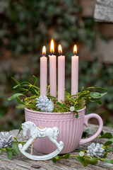 Weihnachtsdekoration mit Schaukelpferdchen, Kerzen und Mistelzweigen in Tasse