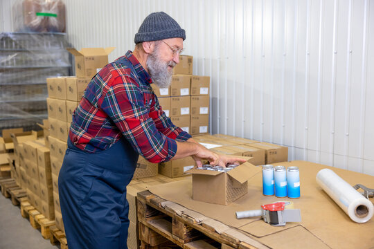 Concentrated plant worker packing canned beverages in the warehouse