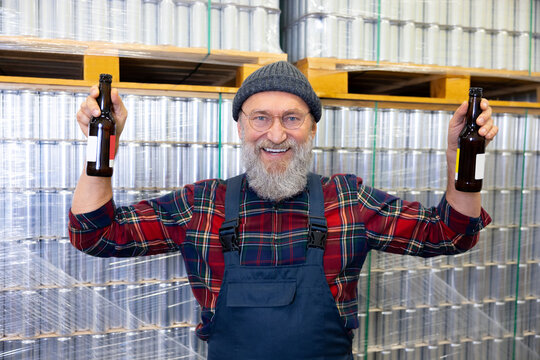 Smiling happy brewer demonstrating bottled beverages before the camera