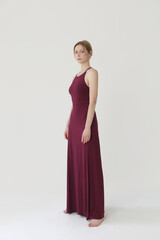 Studio fashion portrait of female model in long tight burgundy jersey dress