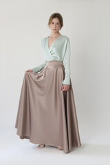 Studio shot of female fashion model in beige maxi circle skirt, Simplistic and elegant silk satin full length skirt