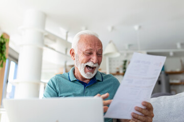 Surprised laughing happy old mature retired man looking through paper document, feeling excited analyzing financial information, getting taxes refund or bank loan approval at home.