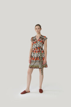 Serie of studio photos of young female model in colorful tropical print sleeveless wrap dress
