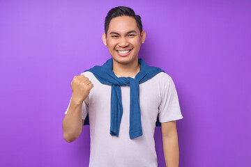 overjoyed and excited young Asian man 20s wearing white t-shirt doing a winner gesture celebrate...