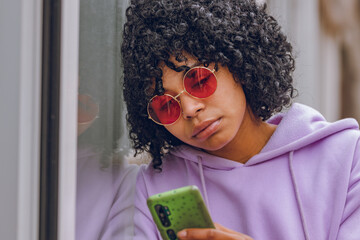 afro girl with sad expression and mobile phone