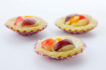 selective focus of mini fruit pie with orange slice and grape slices isolate on white background