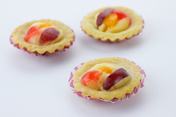 selective focus of mini fruit pie with orange slice and grape slices isolate on white background