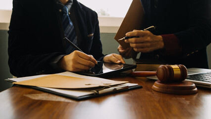 Business and lawyers discussing contract papers with brass scale on desk in office. Law, legal services, advice, justice and law concept picture with film grain effect