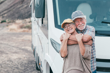 Beautiful senior couple on leisure travel embracing affectionately while standing outside their...