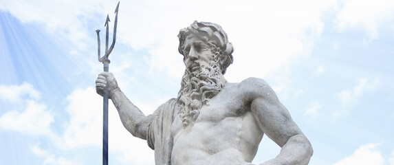 A statue of Neptune in a sunbeam on a blue sky background. Greek mythology
