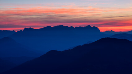 Alpenpanorama kurz vor Sonnenaufgang mit Berg Silhouetten und farbigem Himmel. 