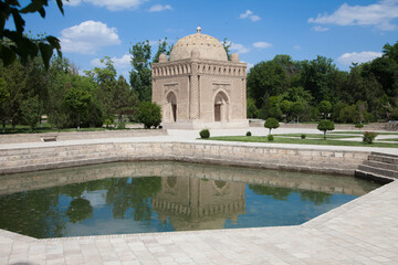 Samanid stone mausoleum in a park next to a swimming pool in Bukhara, Uzbekistan. Tourism, travel concept.