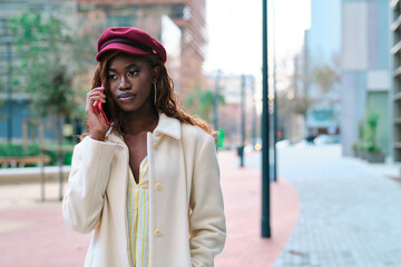 Obraz premium Stylish businesswoman talking on the phone outdoors on the street.
