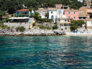 small pretty Mediterranean village resort on coast . Colourful villa taverna beach and blue sea perfect holiday vacation summer destination.