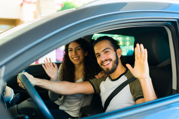 Attractive cheerful waving goodbye in the car