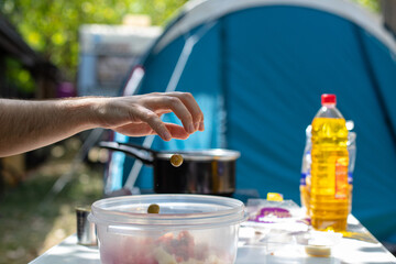 Crop man adding olives into salad