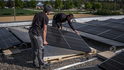 Male team engineers installing stand-alone solar photovoltaic panel system. Electricians mounting blue solar module on roof of modern house. Alternative energy concept