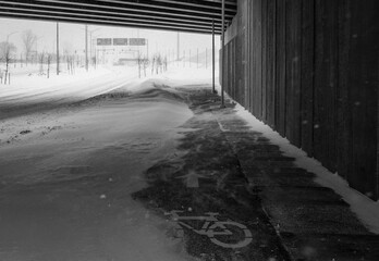Bike path under the snow. Close-up of snow on the road. Impossible to take a bike. Snow storm. Road covered with snow in the middle of a storm, blizzard, winter. cycle route. Climate change