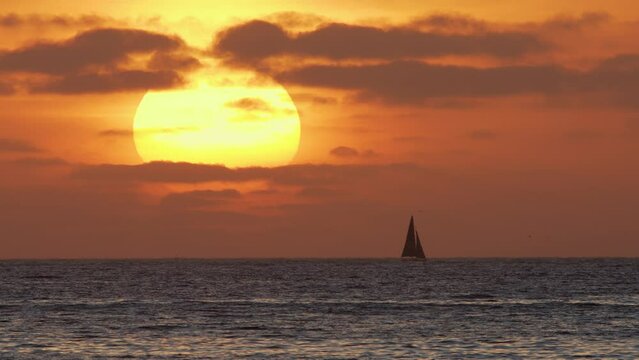 Beautiful evening sunset with a big sun and a sailing yacht in the Atlantic Ocean on the coast of Portugal. 