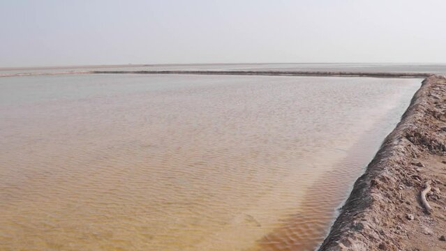 View of salt pans at Little Rann of Kutch, Gujarat, India. Salt pans where water gathers and leaves a deposit of salt on evaporation.

