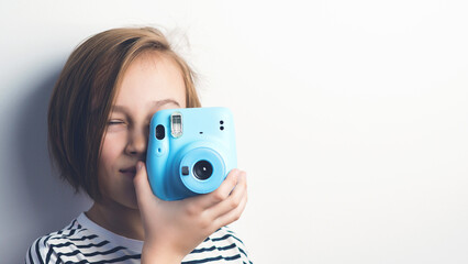 Cute boy holding photo camera. Stylish kid posing over grey background.