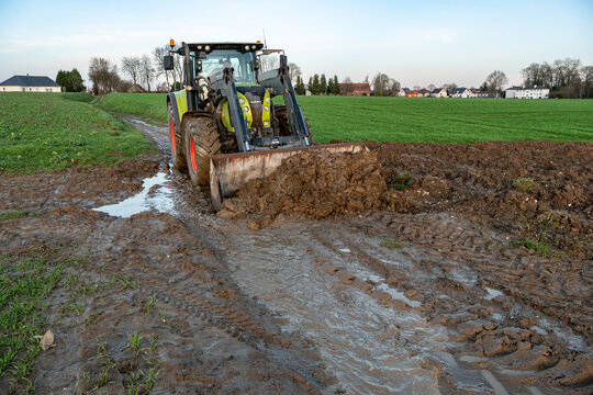 Agriculteur d&eacute;gageant un chemin agricole &agrave; l'aide d'un tracteur suite &agrave; une coul&eacute;e de boue
