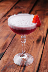 Strawberry alcoholic cocktail with foam on wood