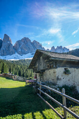 Urige Berghütte in den Dolomiten mit Bergmassiv der Geisslerspitzen im Hintergrund.