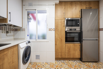 Front of a kitchen with a column of appliances and a stainless steel refrigerator on hydraulic...