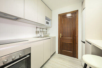 Newly installed kitchen with smooth white cabinets without handles, white stone conglomerate...