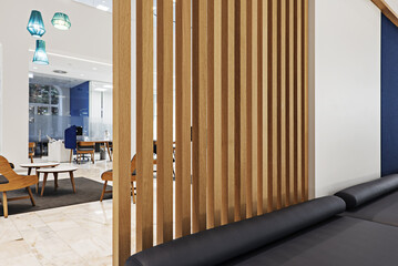 A sofa attached to an oak lattice separating the waiting area from a large living room with offices