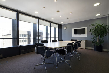 Modern boardroom of a modern office with long wooden table with swivel chairs and newly carpeted floors