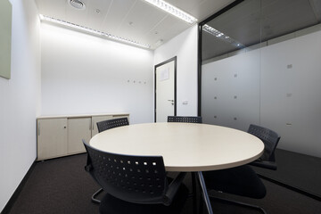 Conference office with blackboard with erasable markers, round table, low filing cabinet, technical ceilings and glass partition