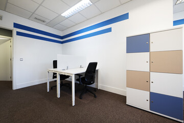 Coworking office with work tables with dividers and colored filing cabinets with locks