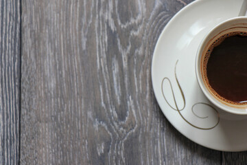 A photo of a white mug with coffee in it, shot on a wooden background.